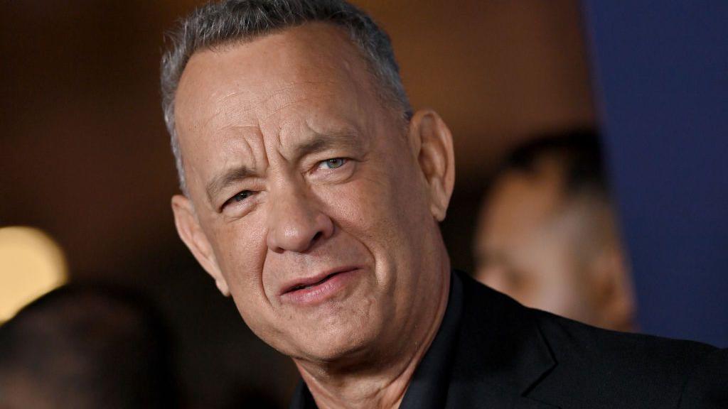 Tom Hanks smiling and waving towards the camera