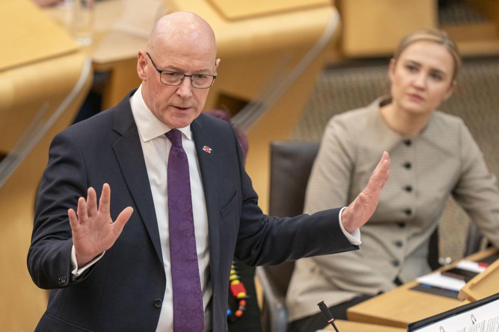 John Swinney standing in Holyrood chamber