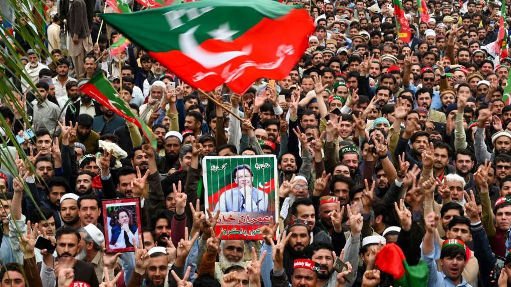 Pakistan Tehreek-e-Insaf (PTI) party supporters hold portraits of Pakistan's former prime minister Imran Khan and wave a PTI flag, which is green and red, as they protest against the alleged skewing in Pakistan's national election, in Peshawar on March 10, 2024