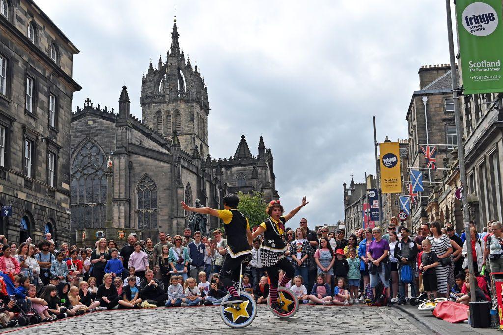 Performers on unicycles entertain a crowd on Edinburgh's Royal Mile in front of St Giles' Cathedral 