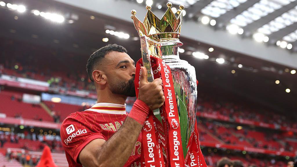 Liverpool winger Mohamed Salah is kissing the Premier League trophy at Anfield.