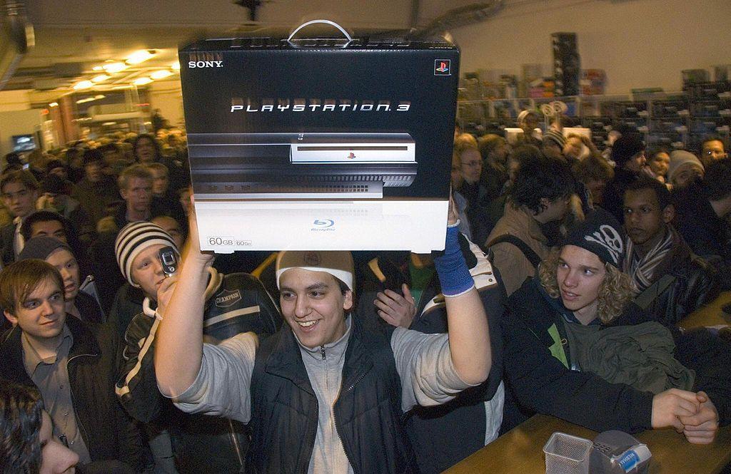 A man holds up the PS3 in a shop after buying it at a launch event. 