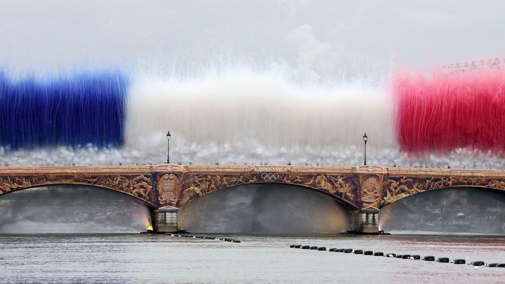 Fireworks are let off on a bridge over the Seine, in the colours of the French flag