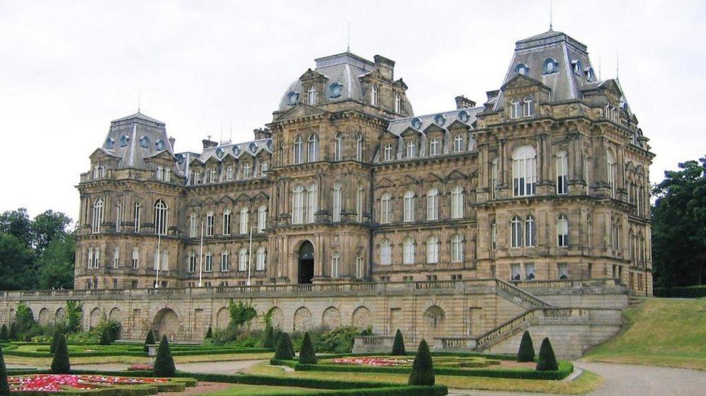 The outside of the Bowes Museum which is a large, four-storey gothic looking building with arched windows. There's a garden in front of the entrance.
