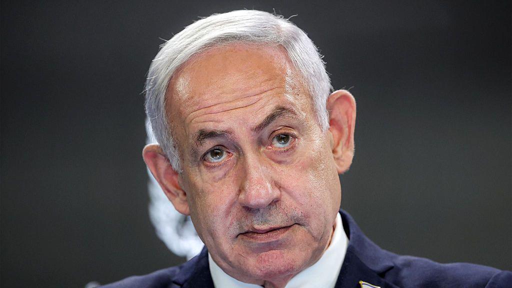 Headshot of Israeli Prime Minister Benjamin Netanyahu staring ahead wearing a dark suit.