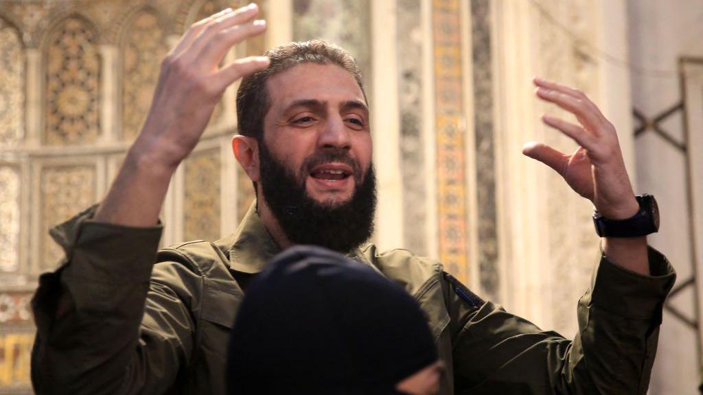 Abu Mohammed al-Jawlani speaking to a crowd of people