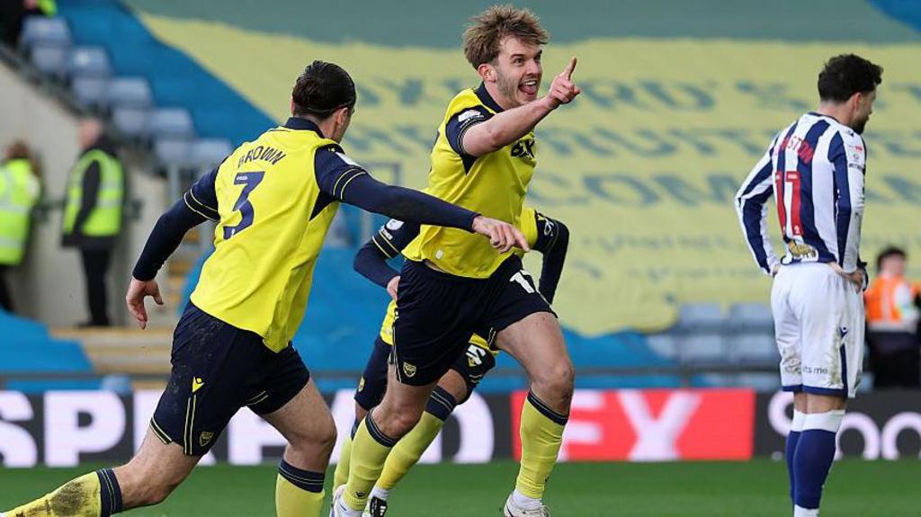 Oxford's Stan Mills raises a finger in celebration after scoring against West Brom