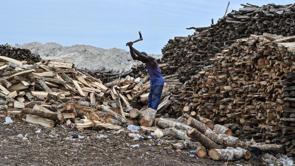 A man chops wood at the Abobodoume beach in Ivory Coast on 30 July 2024.