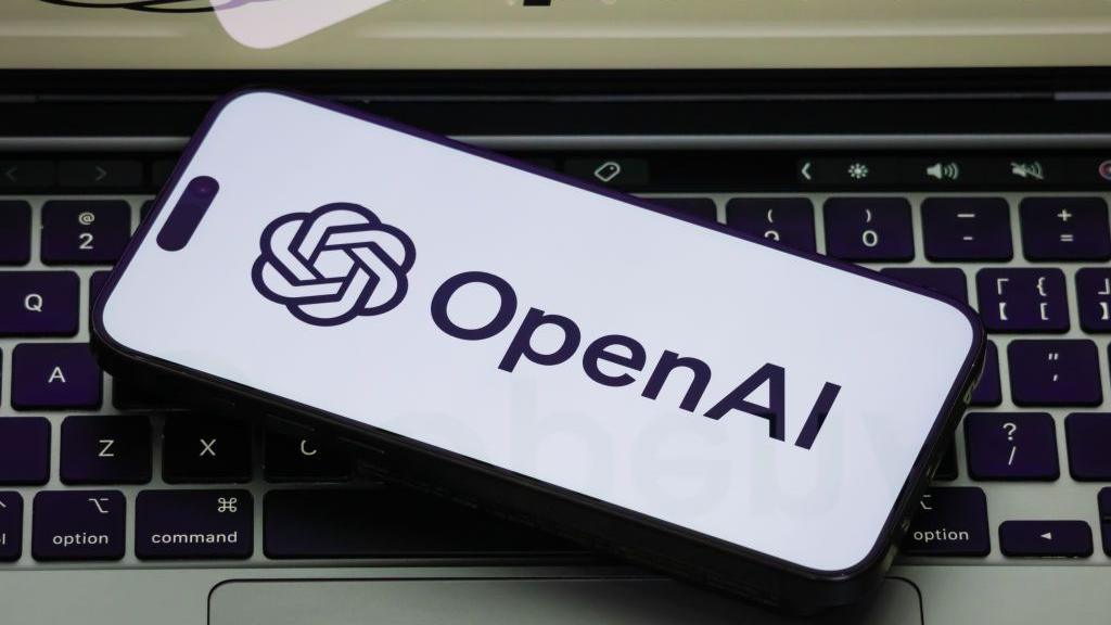 The OpenAI logo on a white phone backgorund, the phone is on a laptop keyboard