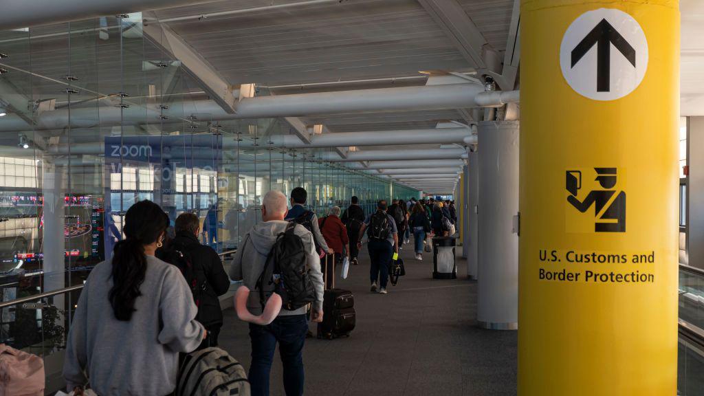 People walking past a U.S. Customs And Border Protection sign at Newark Liberty International Airport.