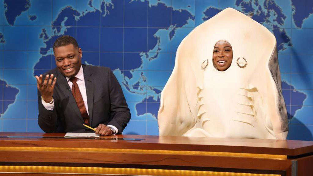 Woman in stingray costume sits next to man