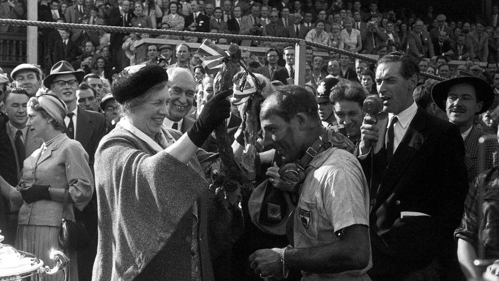 Mirabel Topham, the owner of Aintree racecourse, presents Stirling Moss with the winner's laurel wreath after his victory, with fellow Briton Tony Brooks, in 1957