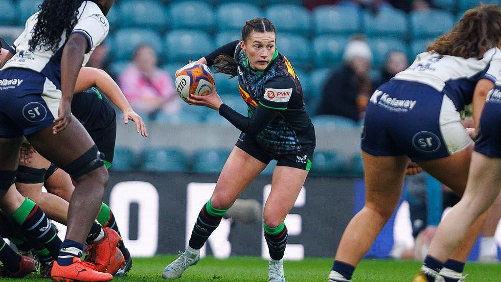 Lucy Packer gets ready to pass the ball from the back of the scrum, wearing Harlequins women kit of dark blue sleeves and various colours front and back