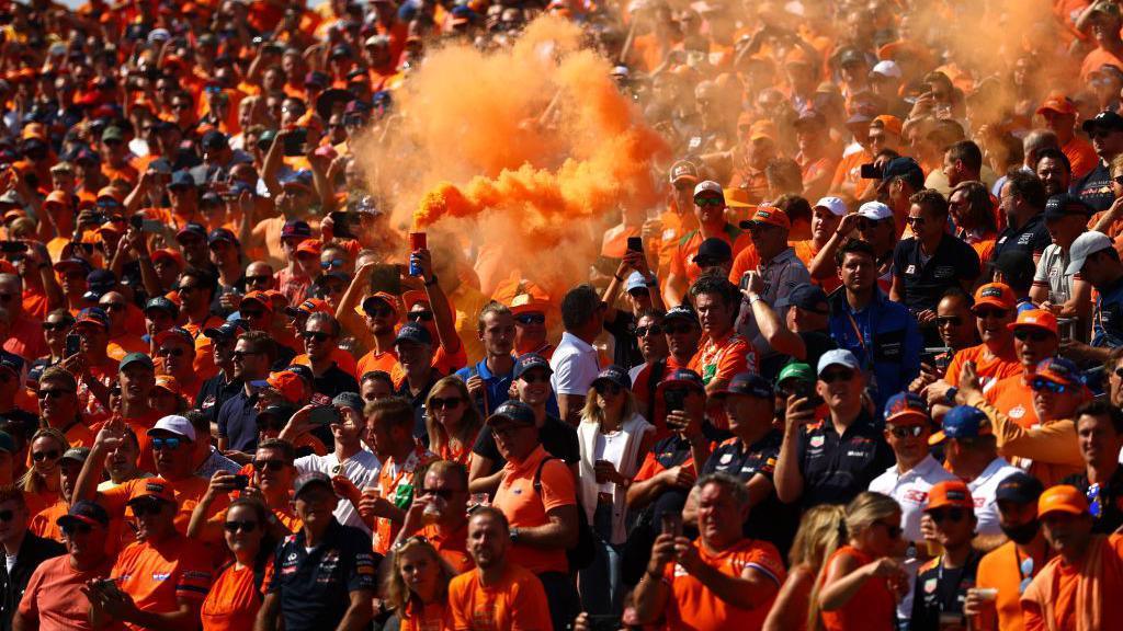 Fans in orange t-shirts hold up flares at the Duth Grand Prix at Zandvoort 