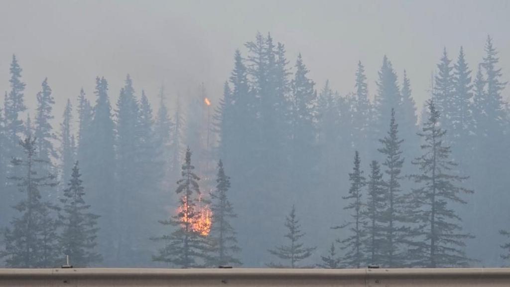 Flames and smoke rise from a burning wildfire, as seen from a highway, in Jasper, Alberta, Canada, July 23, 2024, in this screen grab obtained from a social media video.