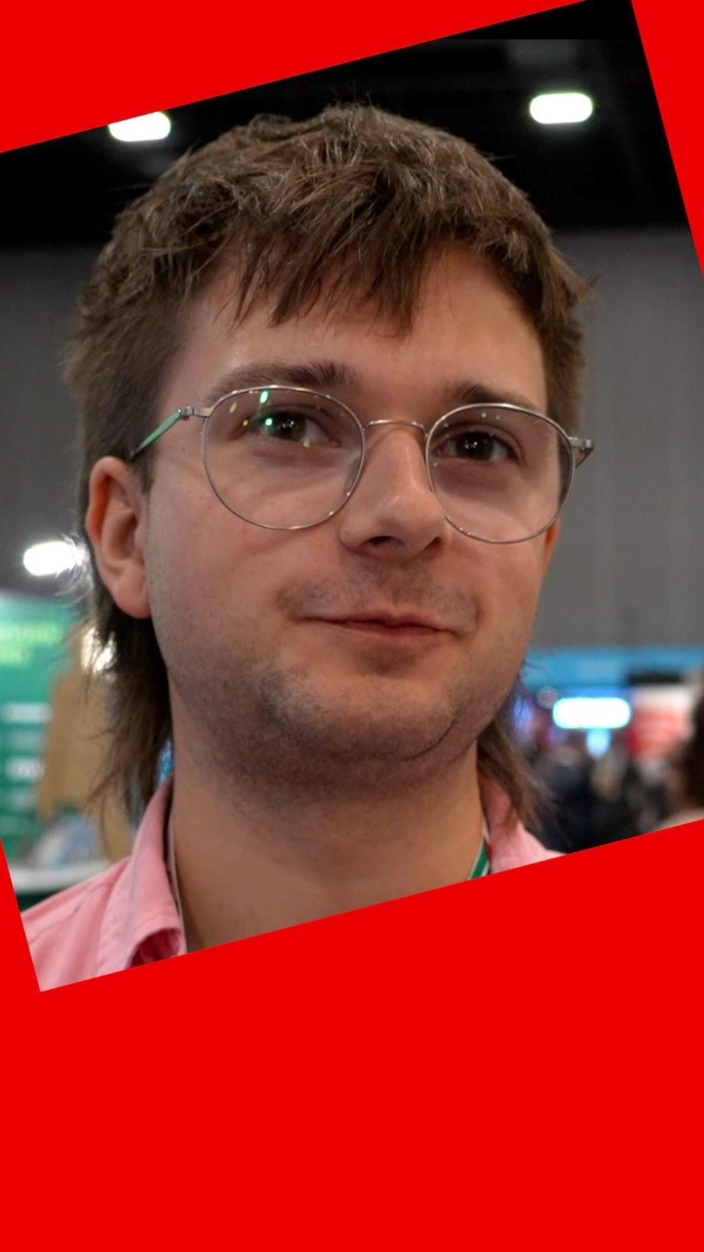 A man with brown hair and round glasses