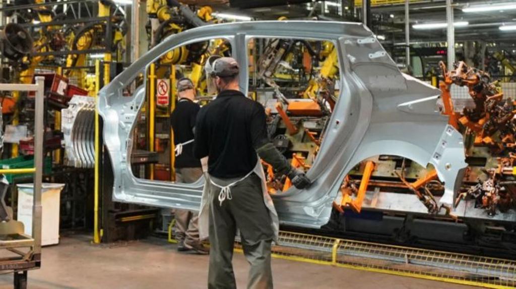 Worker on the production line at Nissan's factory in Sunderland, carrying a car door.