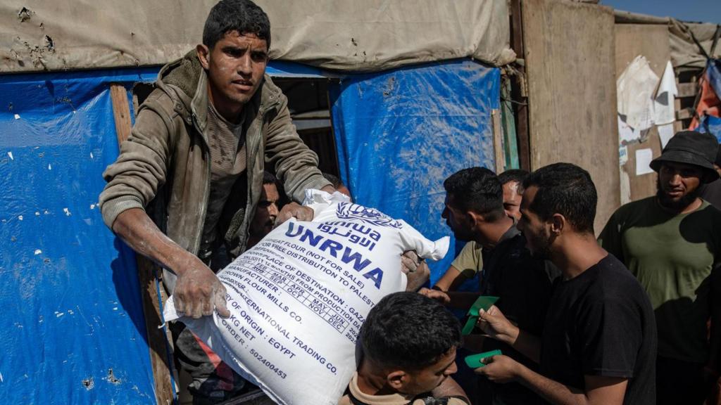 People distribute bags of flour to Palestinians at a United Nations Relief and Works Agency for Palestine Refugees in the Near East (UNRWA) aid distribution center in Khan Younis, southern Gaza Strip, 31 October 2024.