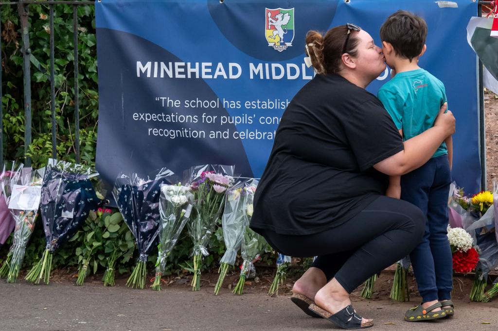 Mum kissing her son near the floral tributes 