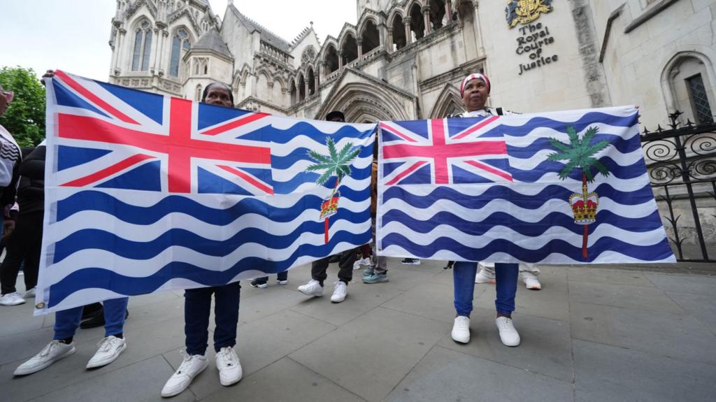 Protesters holding Chagos flags outside court
