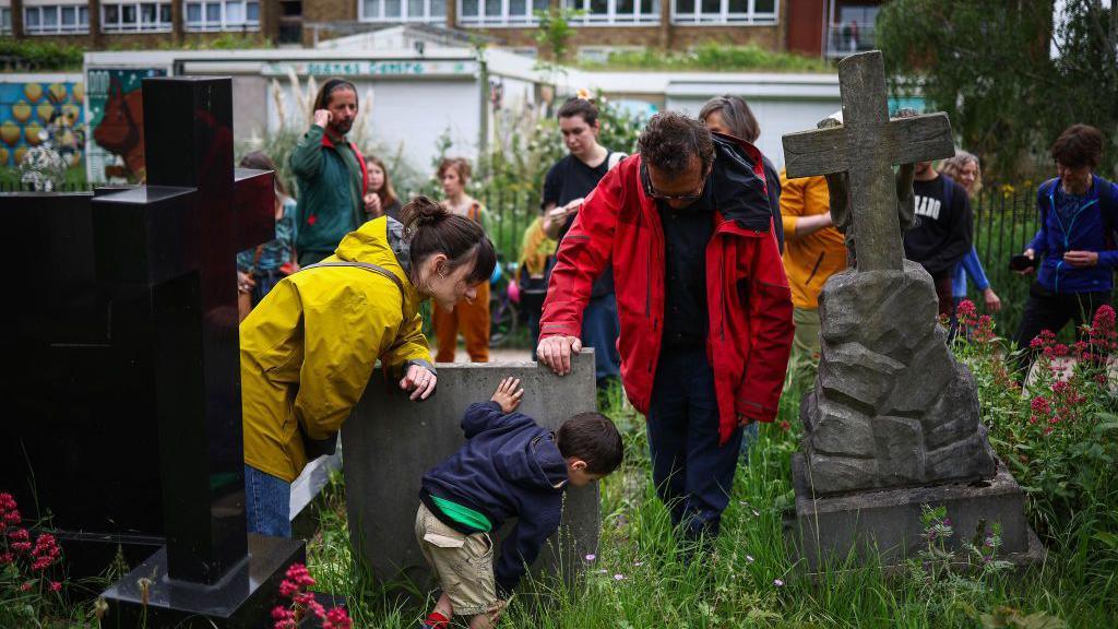 A small group of people are shown how to forage in Tower Hamlets Cemetery Park