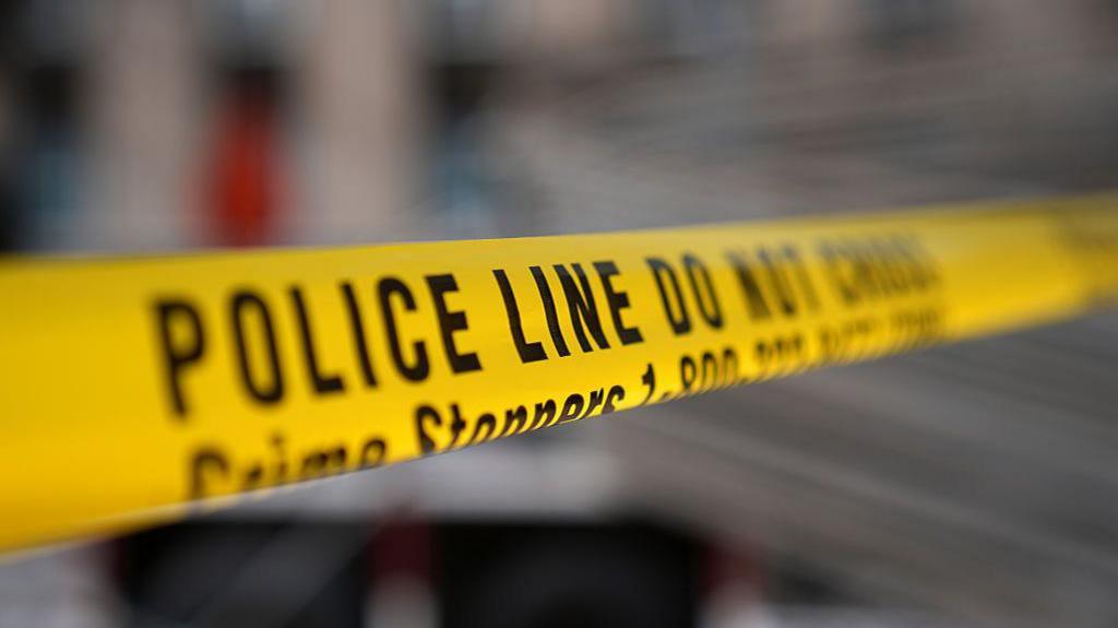 A yellow strip of police tape reads "Police line do not cross".