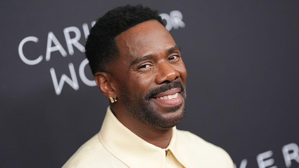 Colman Domingo at Kering Foundation Fourth Annual 'Caring for Women' Dinner in New York at The Pool on September 11, 2025 in New York, New York. He appears smiling at the camera, wearing a cream-coloured collared shirt and a gold earring. 
