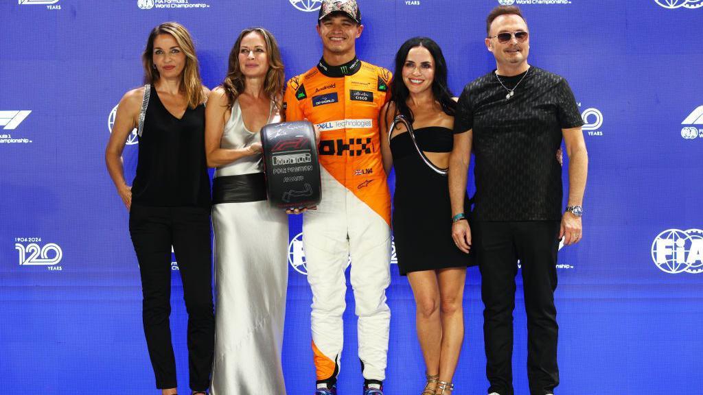 Lando Norris poses for a photograph with Irish pop group The Corrs who presented him with the pole position award