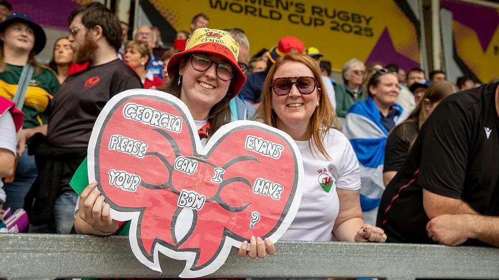 Wales fans with a sign asking for Georgia Evans' bow
