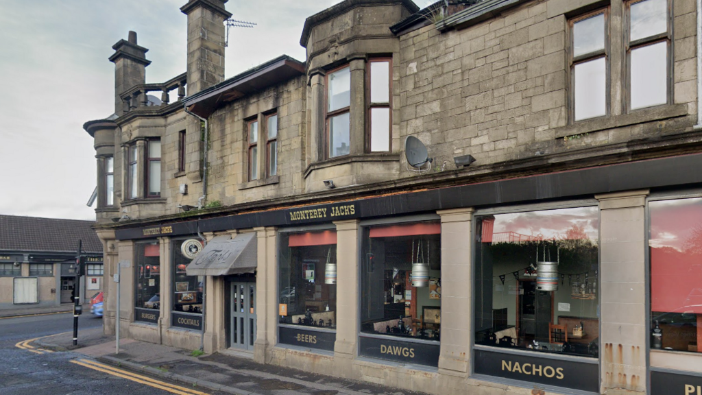 An exterior shot of a restaurant awning and windows in an old tenement style building