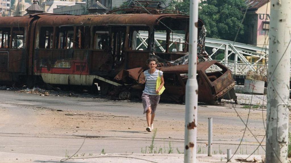 A Bosnian woman runs in the street through an area usually targeted by Serbian snipers in downtown Sarajevo on August 4, 1993