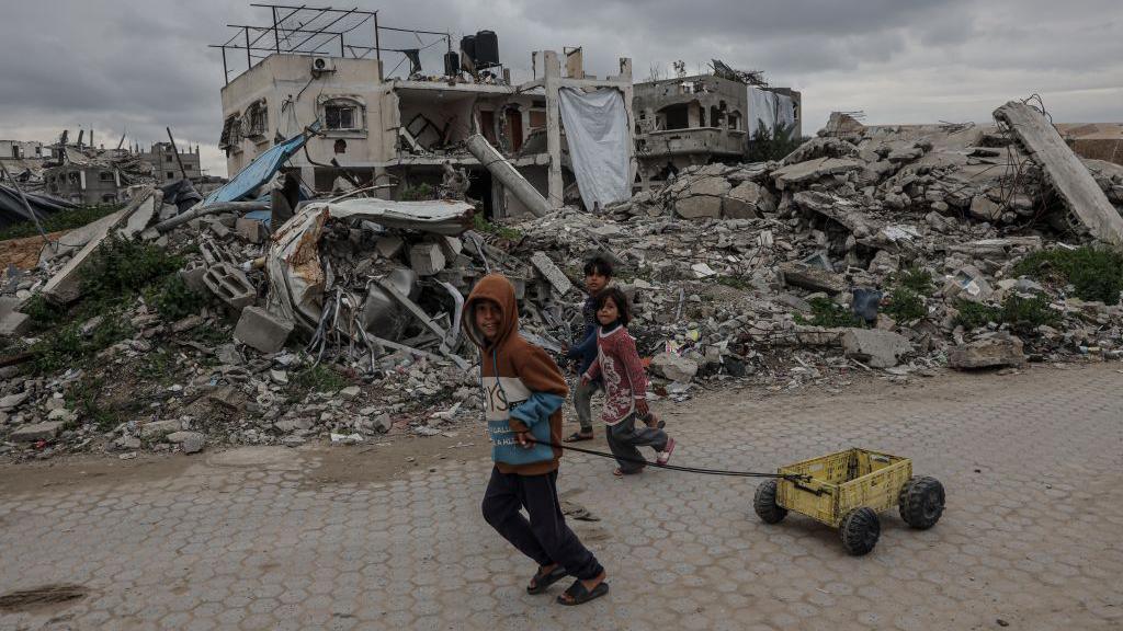 Palestinian children walk past destroyed buildings and makeshift shelters in Beit Lahia, northern Gaza 