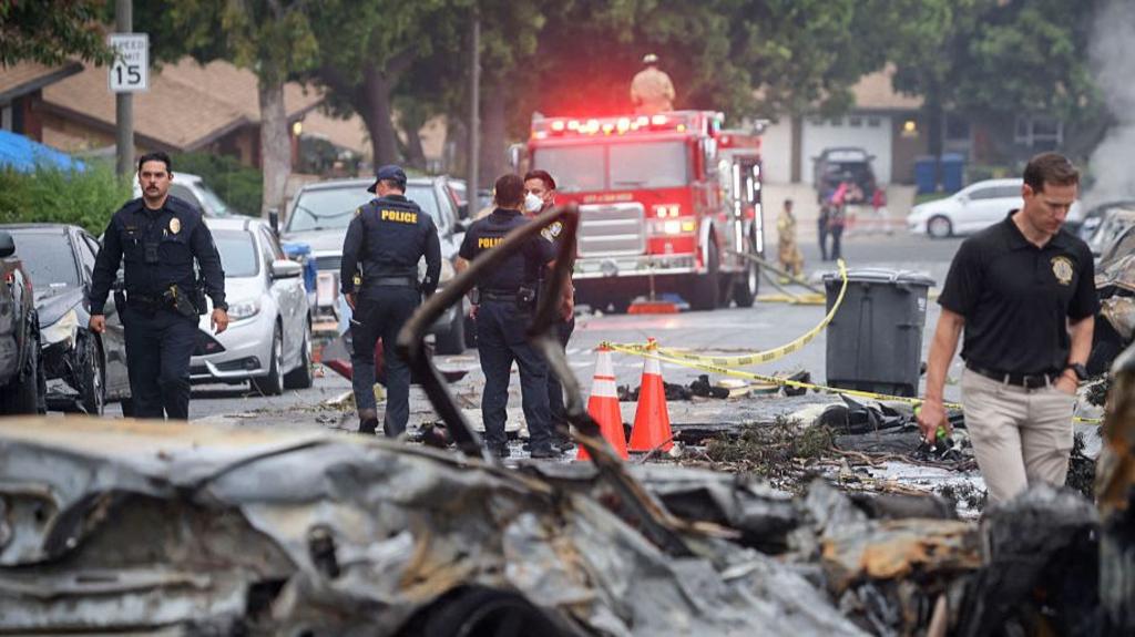 Investigators look through the site ehere a small plane crashed into San Diego, California