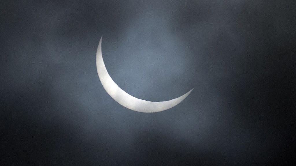 The sun obscuring the moon on a dark, cloudy night. 