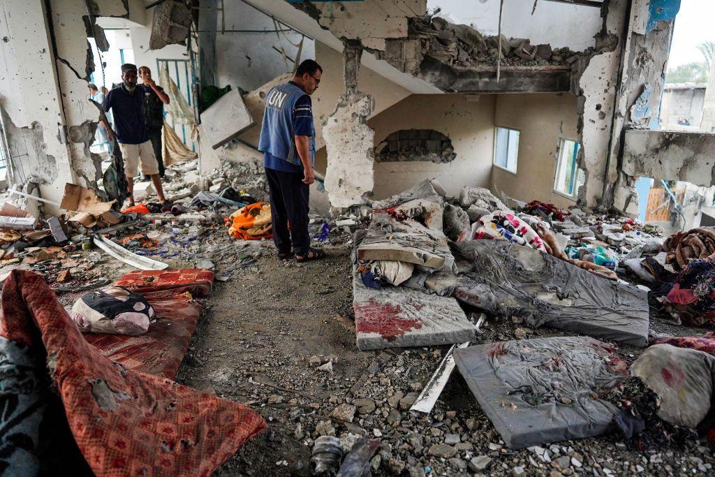 A man wearing a blue UN tabard inspects damage to a UN school in Nuseirat refugee camp, in central Gaza, after it was targeted in an Israeli air strike (6 June 2024)