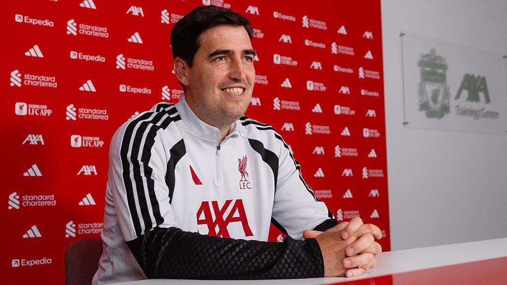 Andoni Iraola sits and smiles Liverpool's AXA training centre media room