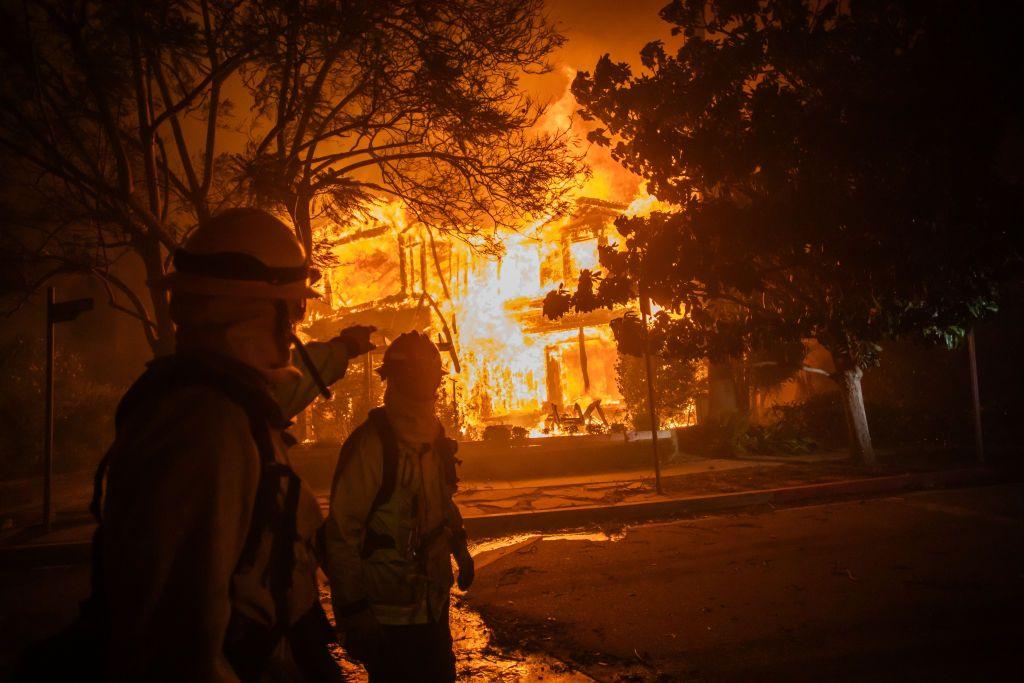 Firefighters walk by house on flames in the in the Pacific Palisades neighbourhood of Los Angeles