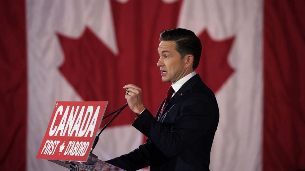 Pierre Poilievre standing before a Canadian flag at his Canada First rally in Ottawa in February 