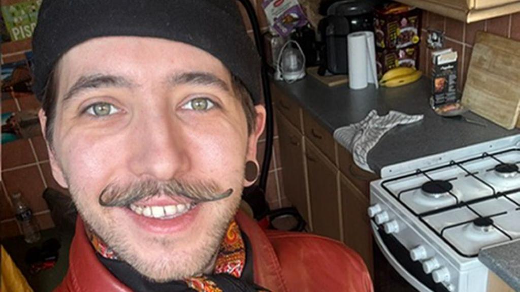 A selfie of Mr Csendes wearing a black hat, patterned neck scarf and red jacket. 