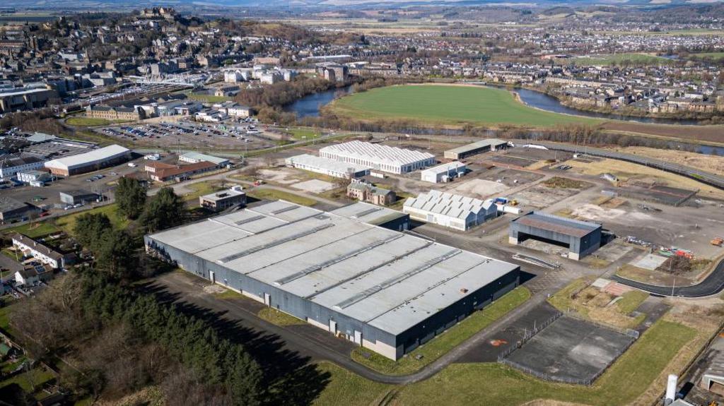 An aerial view of a former military base, with a large flat-roofed building in the foreground.