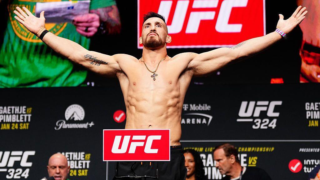 Modestas Bukauskas opens his arms wide as he weighs in