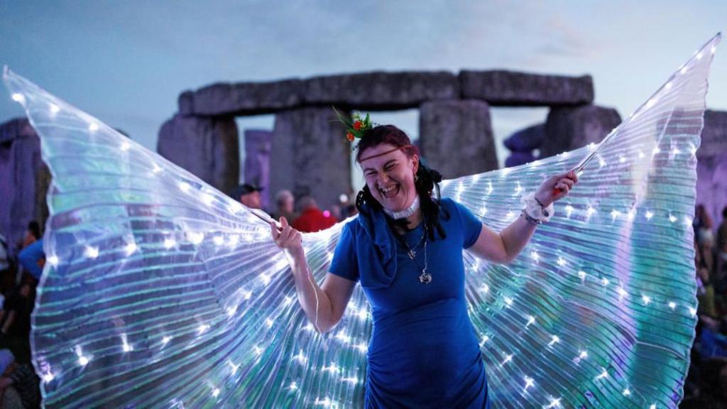 A woman witg butterfly wings in front of Stonehenge