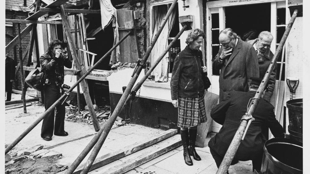 Three men and a woman inspect a pub blown up by a bomb. 