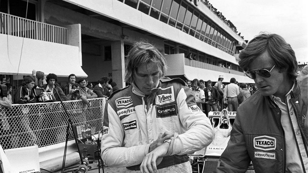 Alistair Caldwell is pictured on the right at the French Grand Prix with James Hunt, who is looking at his watch and is dressed in a F1 kit, in July 1978 in a black and white picture.