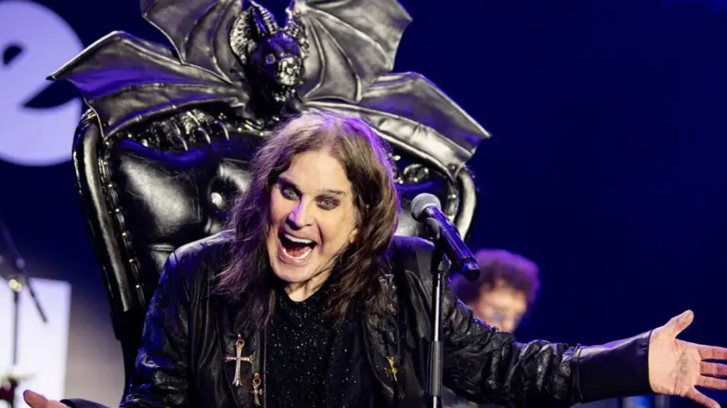 Ozzy Osbourne, dressed in a black leather jacked sat on a black throne with a microphone in front of him