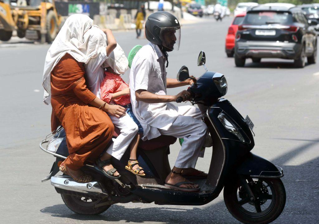 Commuters cover their faces with cloth to shelter from the heat on May 19 in Gurugram