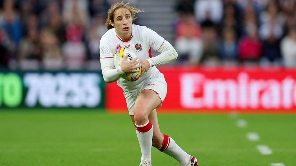 A picture of Red Rose Abby Dow running with the World Cup ball