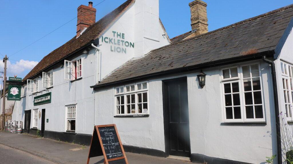 The Ickleton Lion, a large white pub on a sunny day with its first floor windows opened