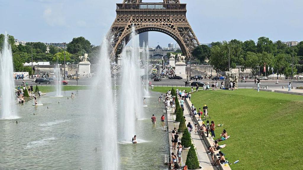 People cool off in the fountains of the Trocadero Gardens, with the Eiffel Tower in the background, in Paris, France, on June 20, 2026. Much of Europe, including France, Spain and Italy, continues to endure a record-breaking heat wave and extreme temperatures. 