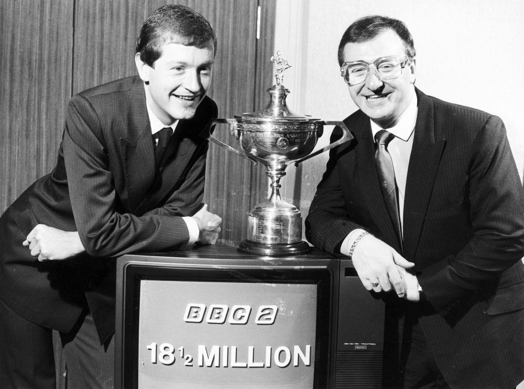 Steve Davis and Dennis Taylor pose with the World Championship trophy and a television on which the screen says 'BBC 2 18 &frac12; million"